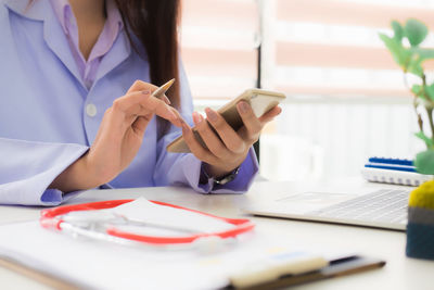 Midsection of woman using mobile phone on table