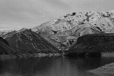 Scenic view of lake by snowcapped mountains against sky