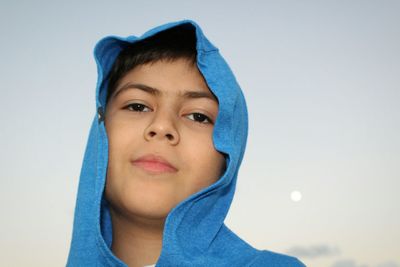 Portrait of boy wearing hood against sky at dusk