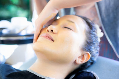 Woman is sleeping while the attendant massages her face with turmeric powder. gently cleanse face.