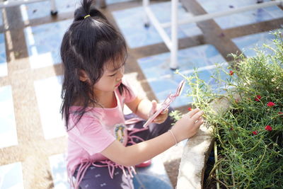 Girl photographing flower through smart phone