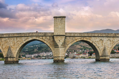 Arch bridge over river against sky