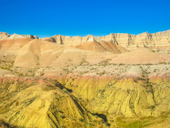 Scenic view of arid landscape against clear blue sky