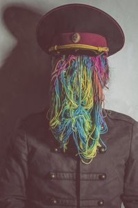 Man with face covered by colorful wool against wall