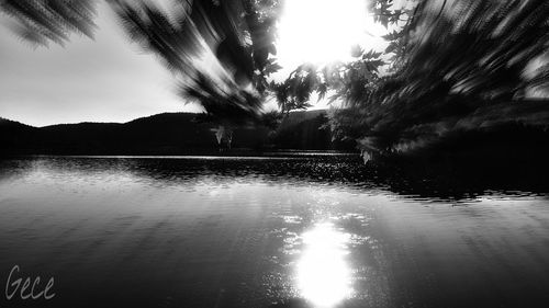 Silhouette trees by lake against sky