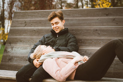 Romantic young couple on bench in park during autumn