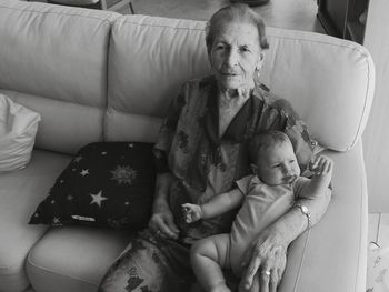 High angle view of grandmother with grandchild sitting on sofa at home