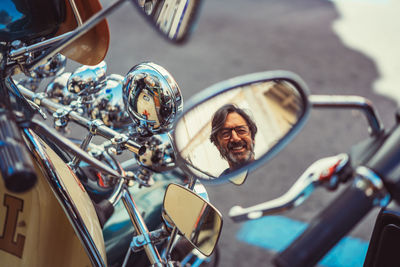 From above motorbike mirror with reflection of cheerful mature man on city street