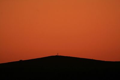 Silhouette built structure against orange sky