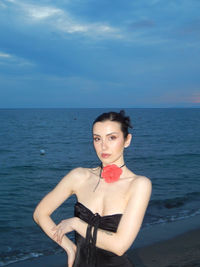 Portrait of young woman looking at sea against sky