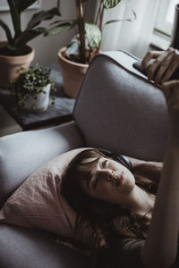 Smiling woman taking selfie while lying on sofa at home