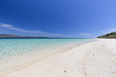 Scenic view of beach against blue sky