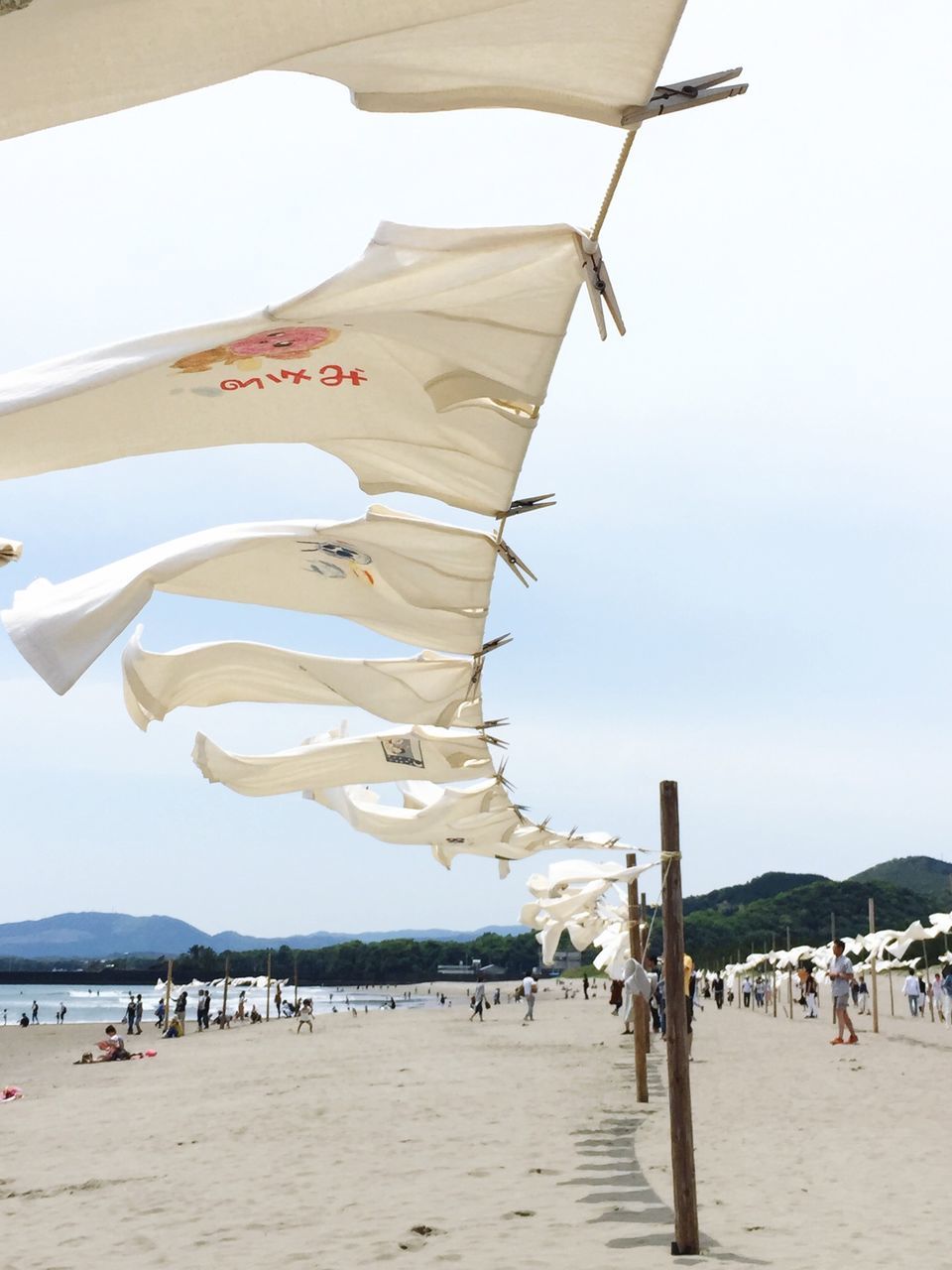 beach, sand, sea, vacations, parasol, large group of people, shore, beach umbrella, flag, tourism, sky, water, clear sky, tourist, leisure activity, identity, day, sunshade, travel destinations