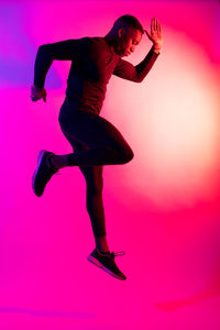 Full length of man standing against pink background