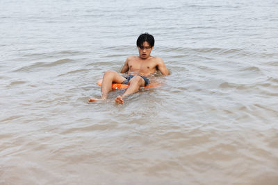 Rear view of shirtless man swimming in sea