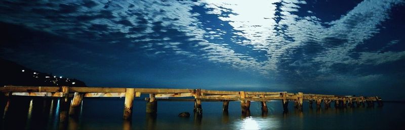 Pier over lake against sky at night