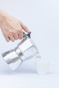 Close-up of hand holding drink against white background