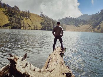 Rear view of man looking at lake against sky