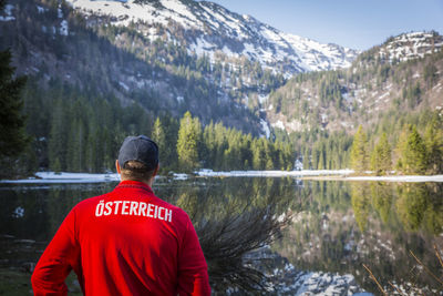 Rear view of man by lake against mountain