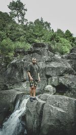 Full length of man standing on rock against waterfall