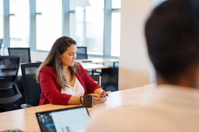 Woman in the meeting in the office using phone