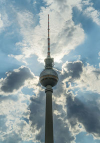 Low angle view of communications tower against cloudy sky