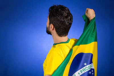 Man holding flag while standing by blue background