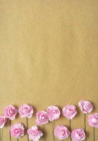 Flat lay with artificial pink roses in the bottom of craft paper.