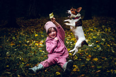 Girl plays with her dog in the autumn forest.