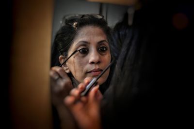 Reflection of woman applying mascara in mirror