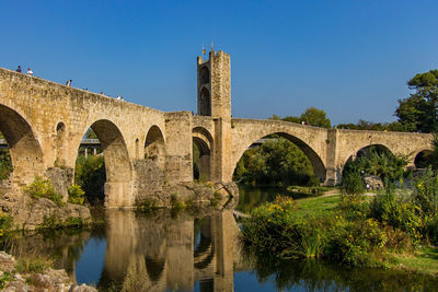 Arch bridge over river against clear sky