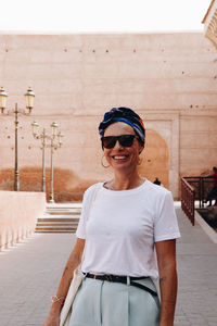 Portrait of young woman standing against wall