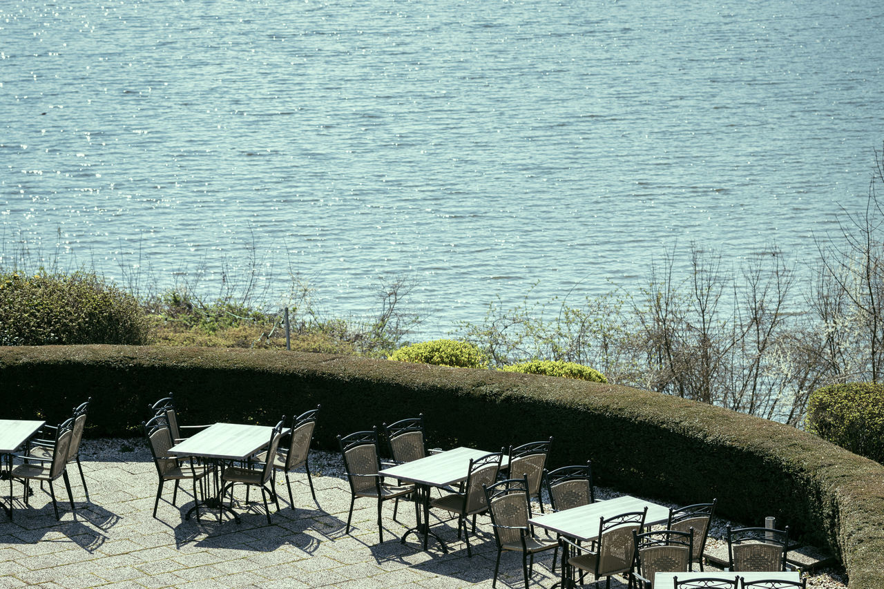 HIGH ANGLE VIEW OF CHAIRS AND TABLE BY LAKE