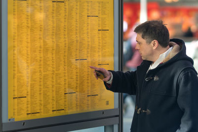 Side view of mature man looking at arrival departure board at station