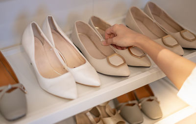 The woman holding shoes in her hands to choose and shopping looking at the shelves of footwear.