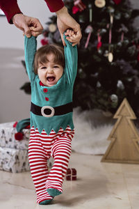 A little 12-month-old christmas elf with a christmas tree and gifts