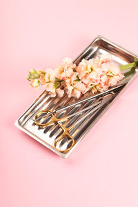 High angle view of dental equipment in tray over pink background