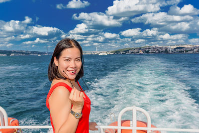 Portrait of smiling woman standing by railing in nautical vessel on sea