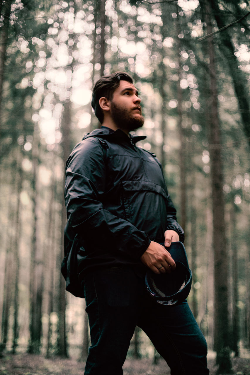 tree, forest, one person, adult, men, clothing, land, nature, black, plant, young adult, woodland, beard, lifestyles, standing, looking, spring, person, facial hair, outdoors, looking away, sports, photo shoot, serious, three quarter length, weapon, protection, leisure activity