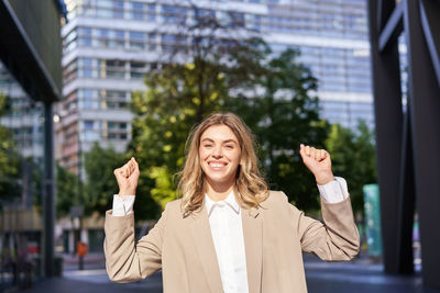 Portrait of young woman standing against building