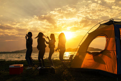 People standing on beach during sunset