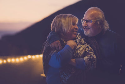 Close-up of cheerful senior couple on building terrace at dusk