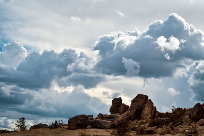 White heart-shaped cloud in gray cloud bank over rocky desert landscape