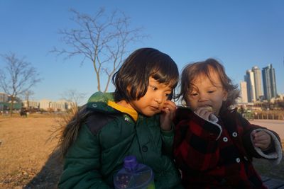 Happy friends wearing warm clothing sitting on field