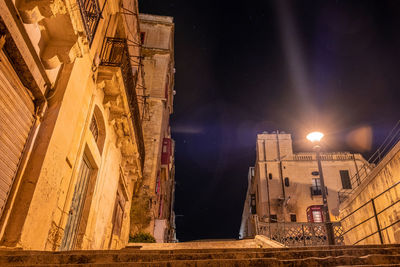 Low angle view of illuminated buildings against sky at night