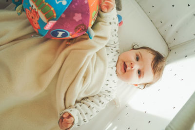 Directly above shot of cute baby girl lying on bed at home