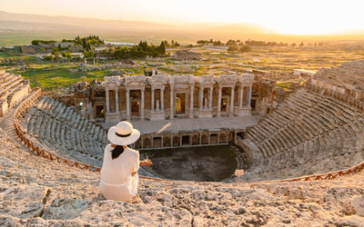 Hierapolis ancient city pamukkale turkey, young woman with hat watching sunset by the ruins unesco