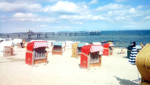 Hooded chairs on beach against sky