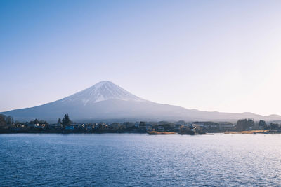 Scenic view of sea and snowcapped mountains against blue sky