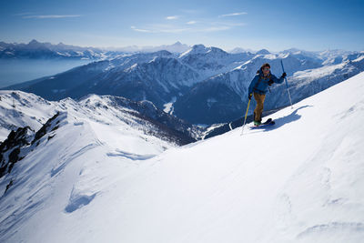 Man in blue jacket ski touring up ridge